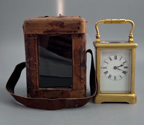 fig 3. A late 19th-century French brass carriage clock housed inside a protective, textured brown leather travelling case with a leather carrying strap.