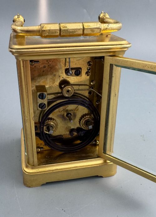 fig 6. A late 19th-century French brass carriage clock housed inside a protective, textured brown leather travelling case with a leather carrying strap.