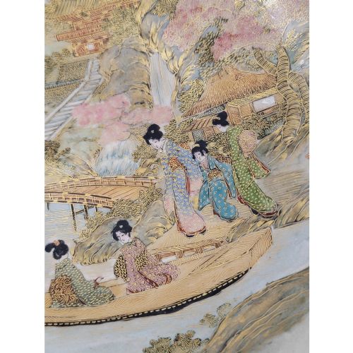 fig 2. A Japanese Satsuma earthenware bowl with hand-painted figures under trees and gold accents, resting on a dark carved wooden stand.