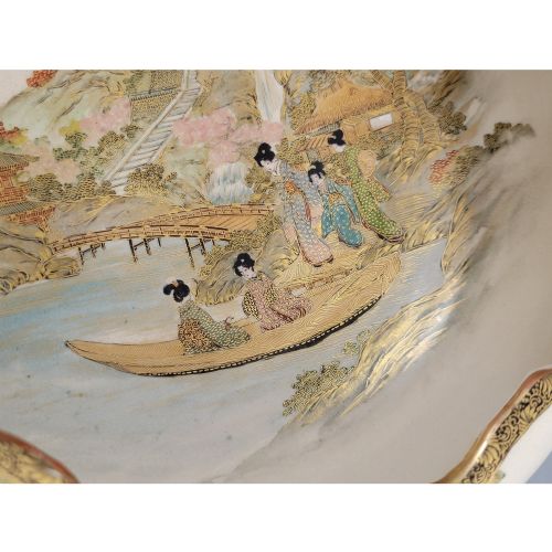 fig 3. A Japanese Satsuma earthenware bowl with hand-painted figures under trees and gold accents, resting on a dark carved wooden stand.