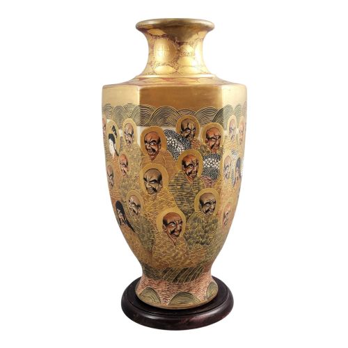 fig 2. A tall gilded Japanese Satsuma earthenware vase painted with figures of Arhats and a dragon, set on a dark wooden base.