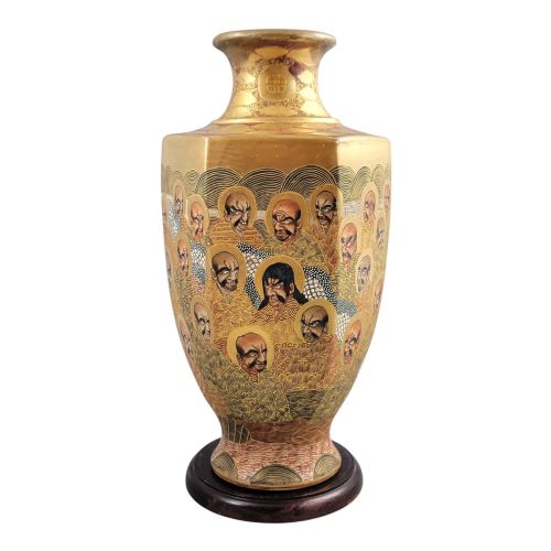 fig 3. A tall gilded Japanese Satsuma earthenware vase painted with figures of Arhats and a dragon, set on a dark wooden base.