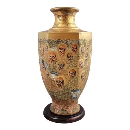 fig 4. A tall gilded Japanese Satsuma earthenware vase painted with figures of Arhats and a dragon, set on a dark wooden base.