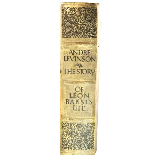 fig 4. The spine of an antique hardcover book featuring intricate gilt floral patterns and lettered text reading The Story of Leon Baksts Life by Andre Levinson.