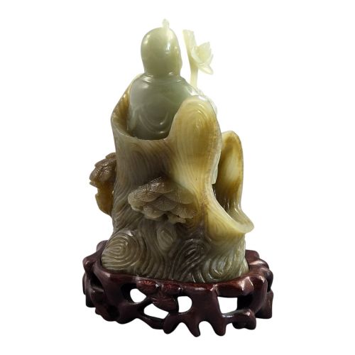fig 4. A carved pale green Chinese jadeite figure holding a lotus stem, resting on a fitted dark carved wooden stand.