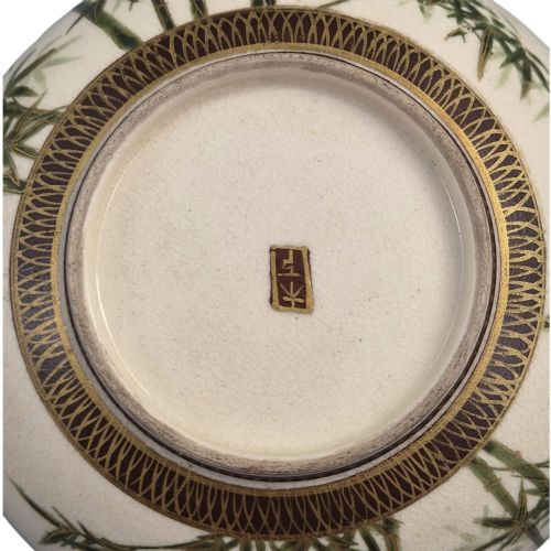 fig 2. An antique cream earthenware bowl resting on a carved wooden base, decorated inside with hand-painted Japanese landscapes and figures, and finished with a bamboo pattern around the exterior.