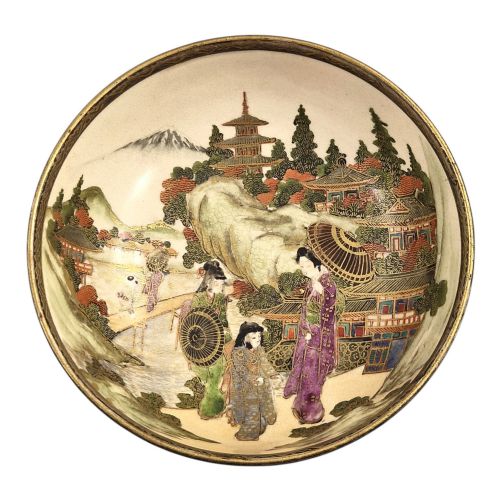 fig 4. An antique cream earthenware bowl resting on a carved wooden base, decorated inside with hand-painted Japanese landscapes and figures, and finished with a bamboo pattern around the exterior.