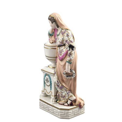 fig 2. A Neoclassical porcelain figure depicting a draped female leaning against a gilded urn on a pedestal.