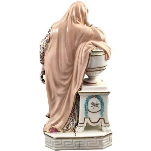 fig 4. A Neoclassical porcelain figure depicting a draped female leaning against a gilded urn on a pedestal.
