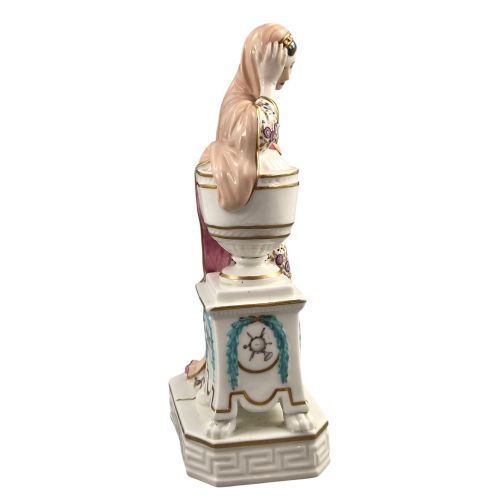 fig 5. A Neoclassical porcelain figure depicting a draped female leaning against a gilded urn on a pedestal.