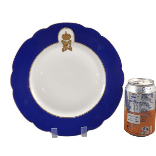 fig 2. A white round porcelain plate featuring a thick cobalt blue scalloped border and a gilded Imperial monogram topped with a crown.