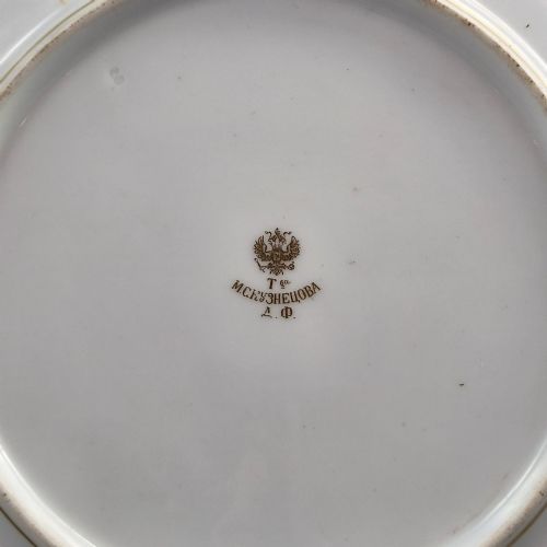 fig 5. A white round porcelain plate featuring a thick cobalt blue scalloped border and a gilded Imperial monogram topped with a crown.