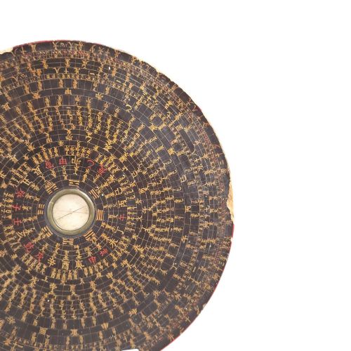 fig 4. A circular antique Chinese Luopan geomantic compass crafted from dark lacquered wood featuring multiple concentric rings of gilded Chinese characters and a central brass magnetic dial.