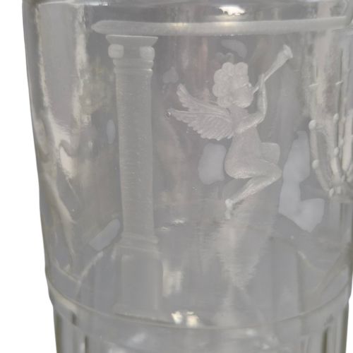 fig 4. A large clear glass beaker featuring detailed wheel-engraved ceremonial iconography, vertical fluted panels near the lower rim, and a faceted base.