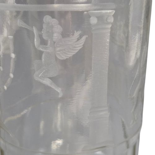 fig 6. A large clear glass beaker featuring detailed wheel-engraved ceremonial iconography, vertical fluted panels near the lower rim, and a faceted base.