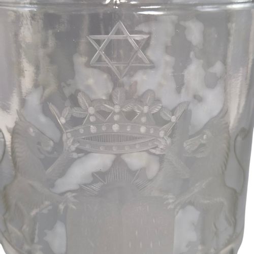 fig 9. A large clear glass beaker featuring detailed wheel-engraved ceremonial iconography, vertical fluted panels near the lower rim, and a faceted base.