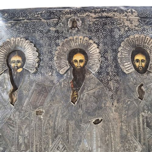 fig 3. A rectangular antique Orthodox silver icon featuring repousse depictions of the Three Holy Hierarchs with detailed halos and Cyrillic script along the bottom edge.