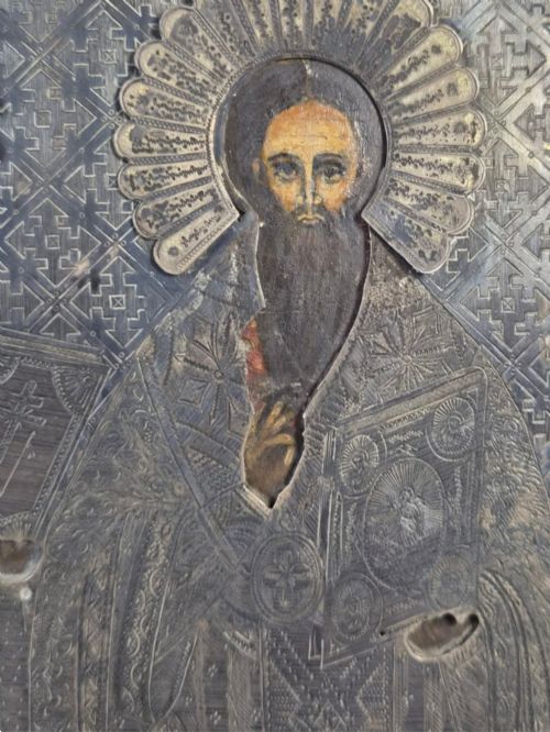 fig 6. A rectangular antique Orthodox silver icon featuring repousse depictions of the Three Holy Hierarchs with detailed halos and Cyrillic script along the bottom edge.