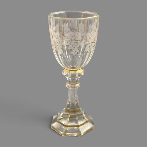 fig 2. A clear Bohemian crystal romer goblet featuring wheel-engraved grapevine motifs, a faceted stem, and gilt highlight accents on a hexagonal foot.