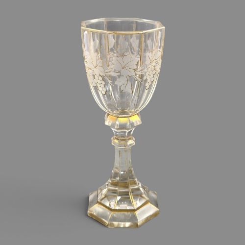 fig 5. A clear Bohemian crystal romer goblet featuring wheel-engraved grapevine motifs, a faceted stem, and gilt highlight accents on a hexagonal foot.