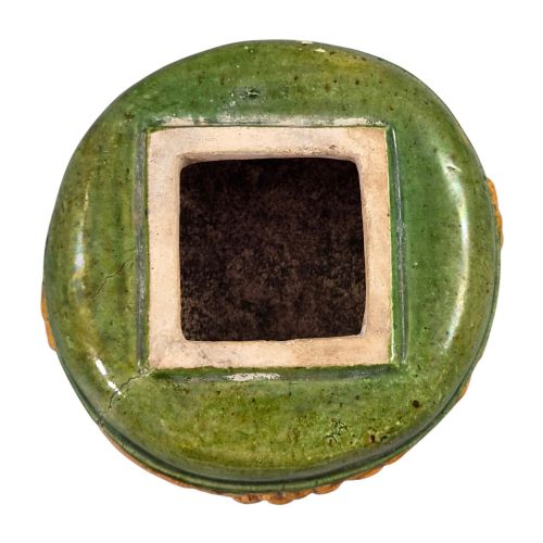 fig 4. A squat antique Chinese ceramic water vessel featuring a green glazed upper shoulder, a square rim, and an amber-glazed moulded floral band around the middle.
