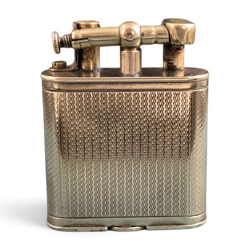 fig 2. A 1920s Dunhill Unique gold-plated petrol lighter featuring an engine-turned pattern and a straight-arm lift mechanism.