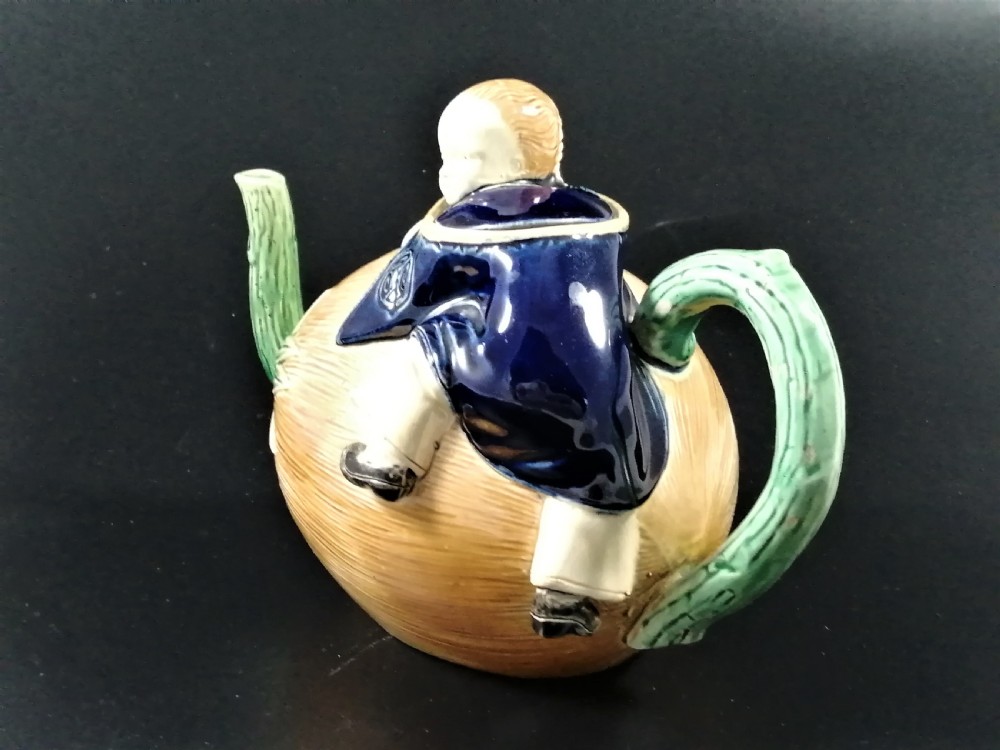 A Victorian earthenware majolica teapot shaped as a melon with a figure of a boy in a blue jacket seated on top forming the lid. View II
