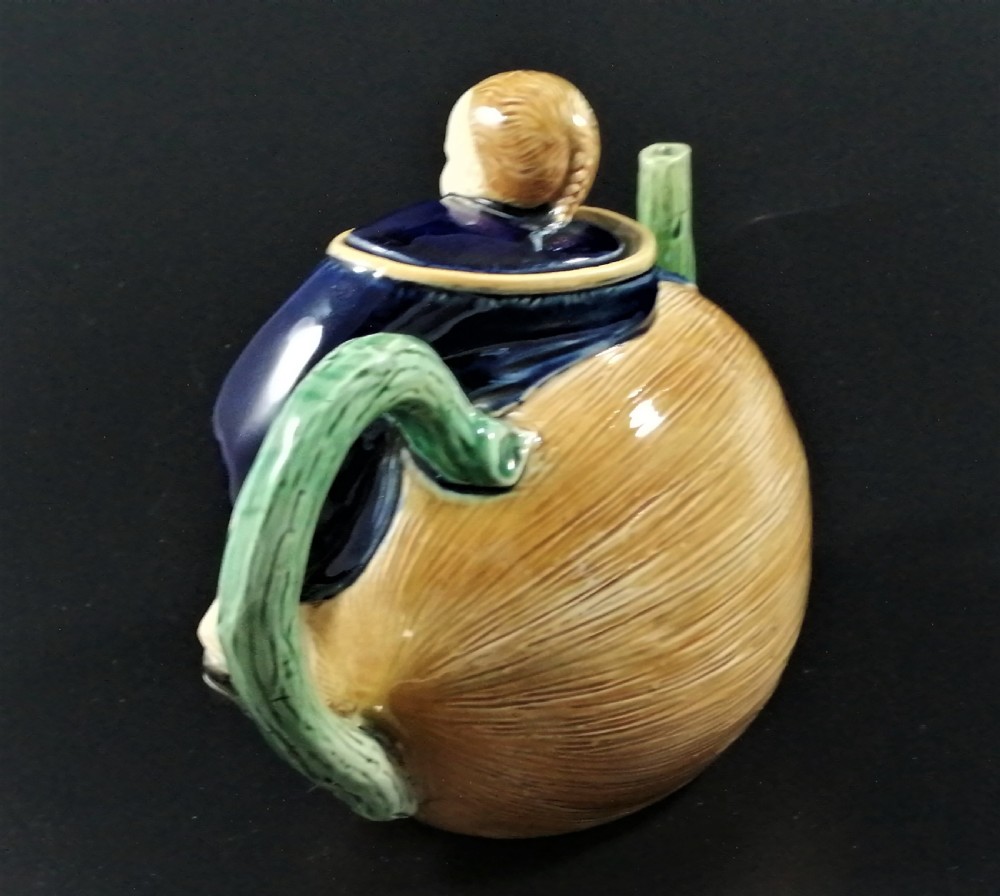 A Victorian earthenware majolica teapot shaped as a melon with a figure of a boy in a blue jacket seated on top forming the lid. View III