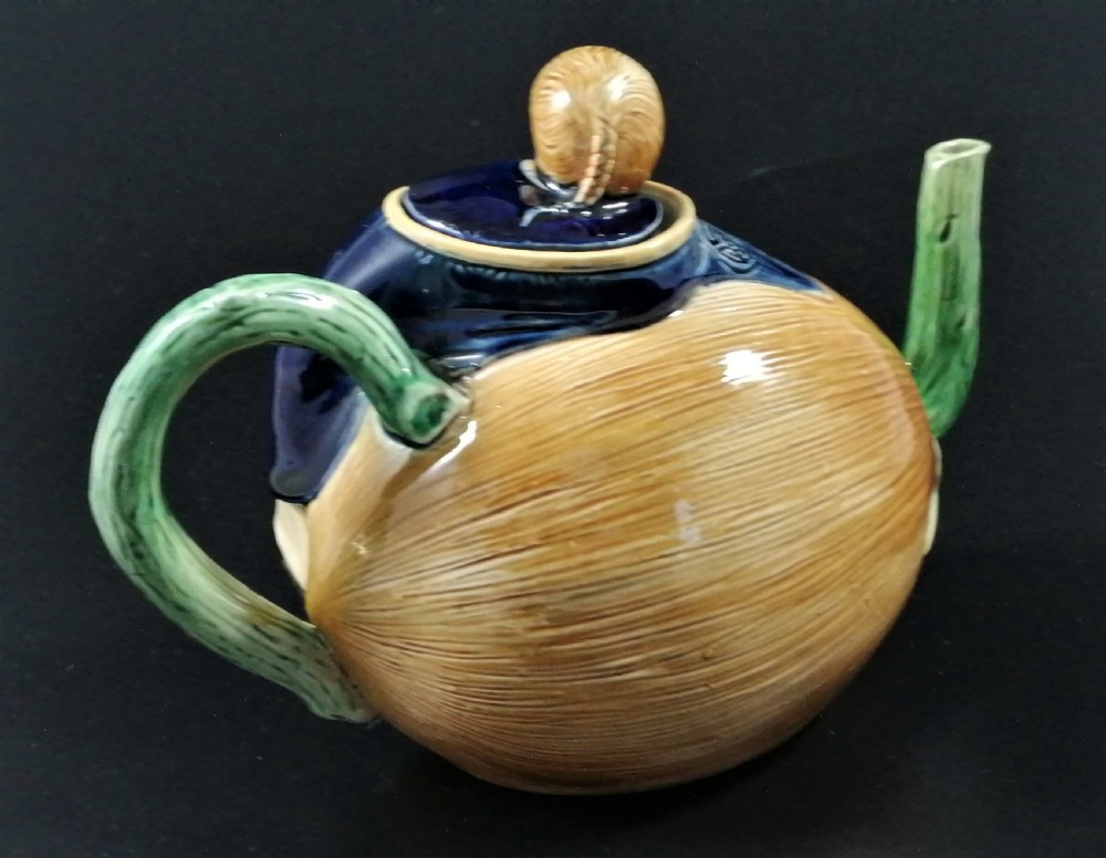A Victorian earthenware majolica teapot shaped as a melon with a figure of a boy in a blue jacket seated on top forming the lid. View IV
