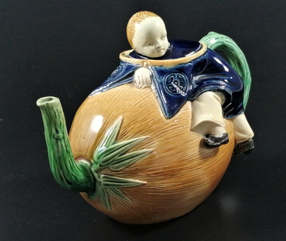 A Victorian earthenware majolica teapot shaped as a melon with a figure of a boy in a blue jacket seated on top forming the lid. View VIII