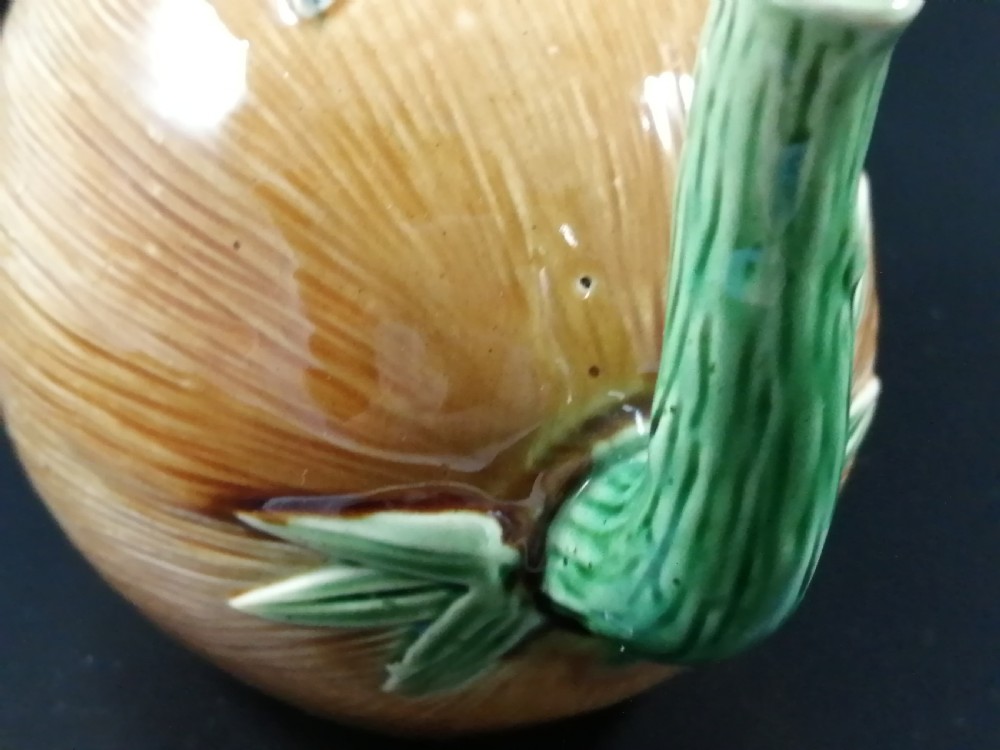 A Victorian earthenware majolica teapot shaped as a melon with a figure of a boy in a blue jacket seated on top forming the lid. View IX
