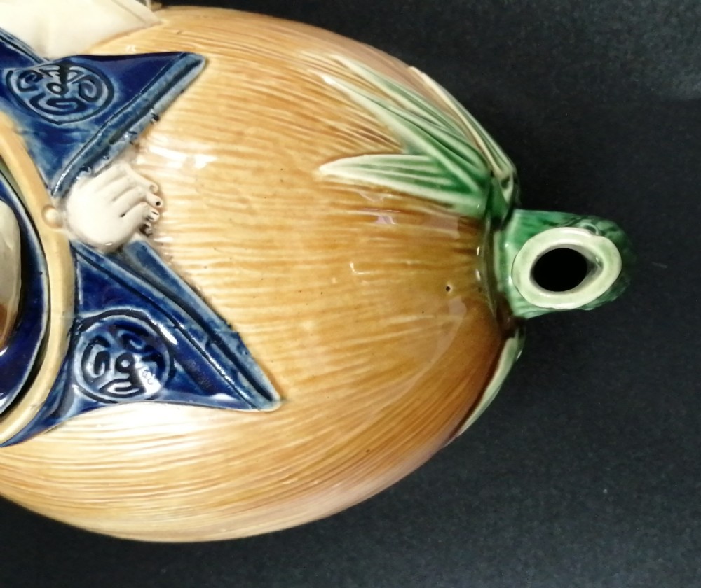 A Victorian earthenware majolica teapot shaped as a melon with a figure of a boy in a blue jacket seated on top forming the lid. View XII