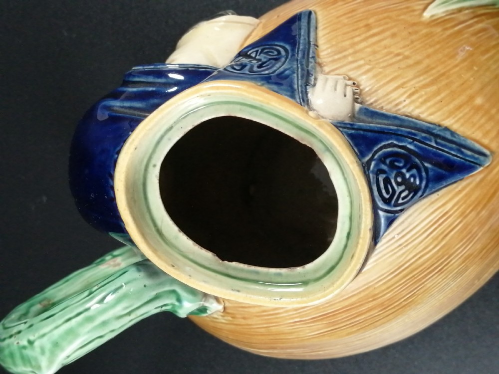 A Victorian earthenware majolica teapot shaped as a melon with a figure of a boy in a blue jacket seated on top forming the lid. View XIII