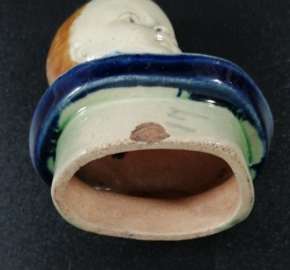 A Victorian earthenware majolica teapot shaped as a melon with a figure of a boy in a blue jacket seated on top forming the lid. View XVI