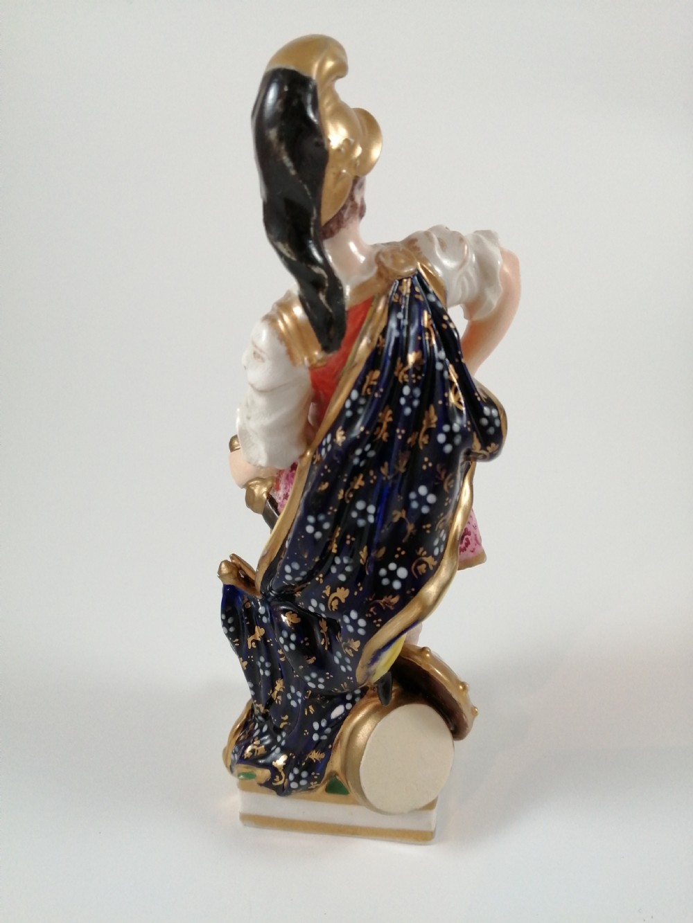 An antique hand-painted porcelain figure depicting the Roman god Mars in gilded armour, a pink tunic, and a golden helmet, standing on a green base. View V