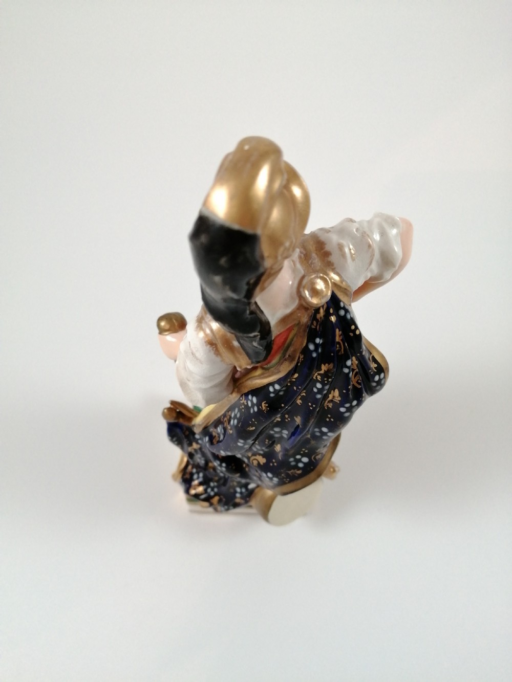 An antique hand-painted porcelain figure depicting the Roman god Mars in gilded armour, a pink tunic, and a golden helmet, standing on a green base. View XIII
