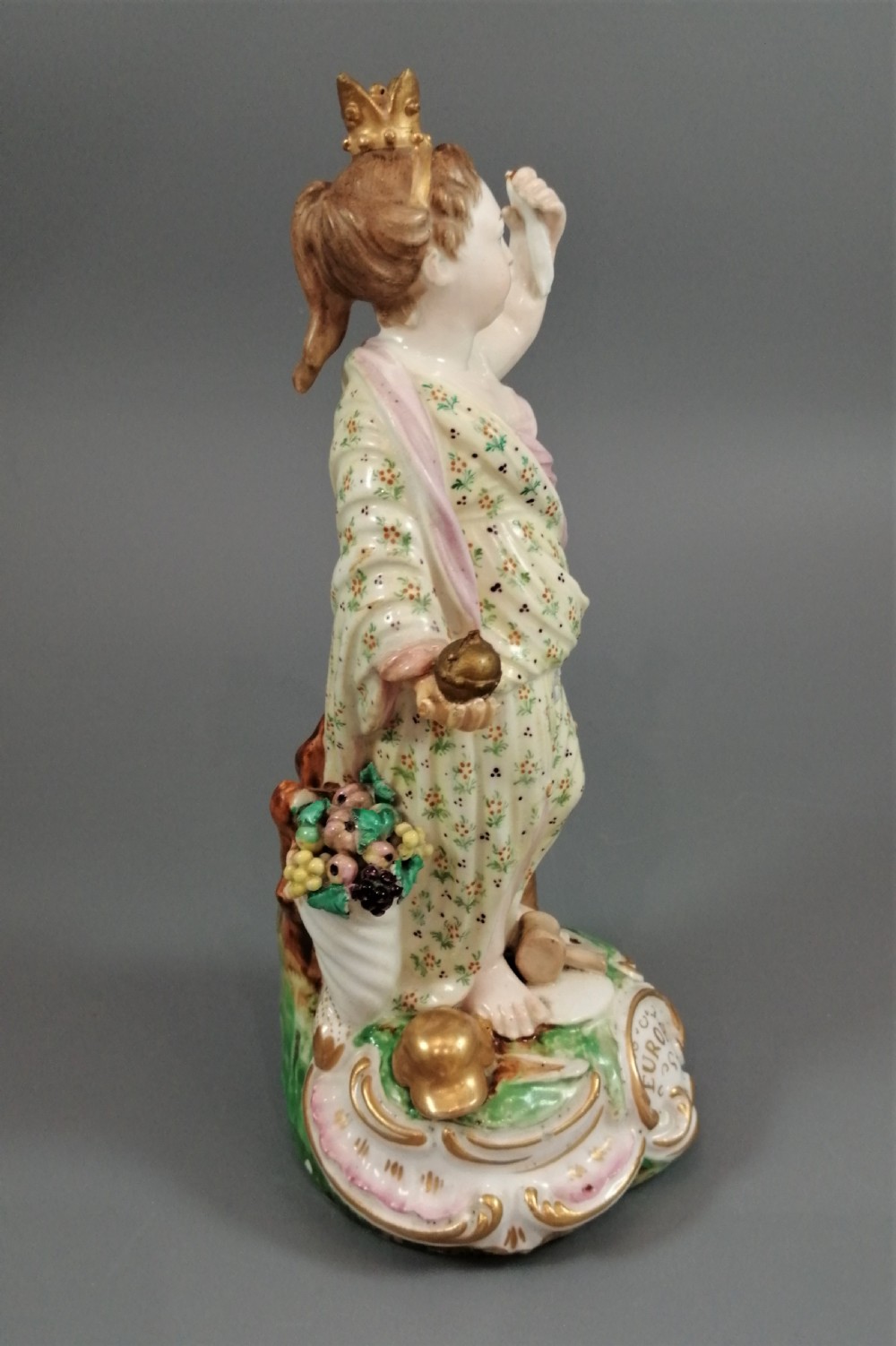 An 18th-century Derby soft-paste porcelain statuette representing Europe, featuring a crowned figure in patterned drapery standing on a gilded scrollwork base. View II