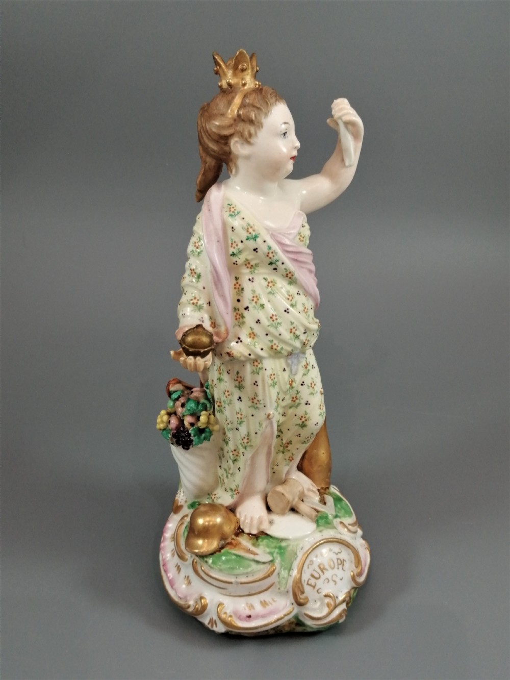 An 18th-century Derby soft-paste porcelain statuette representing Europe, featuring a crowned figure in patterned drapery standing on a gilded scrollwork base. View III