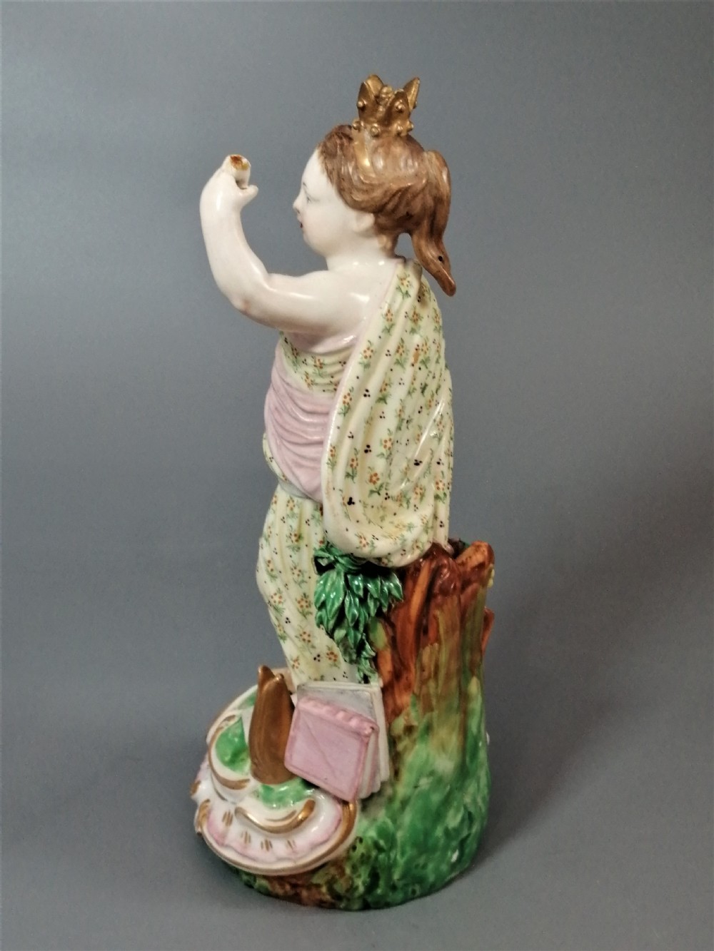 An 18th-century Derby soft-paste porcelain statuette representing Europe, featuring a crowned figure in patterned drapery standing on a gilded scrollwork base. View IX
