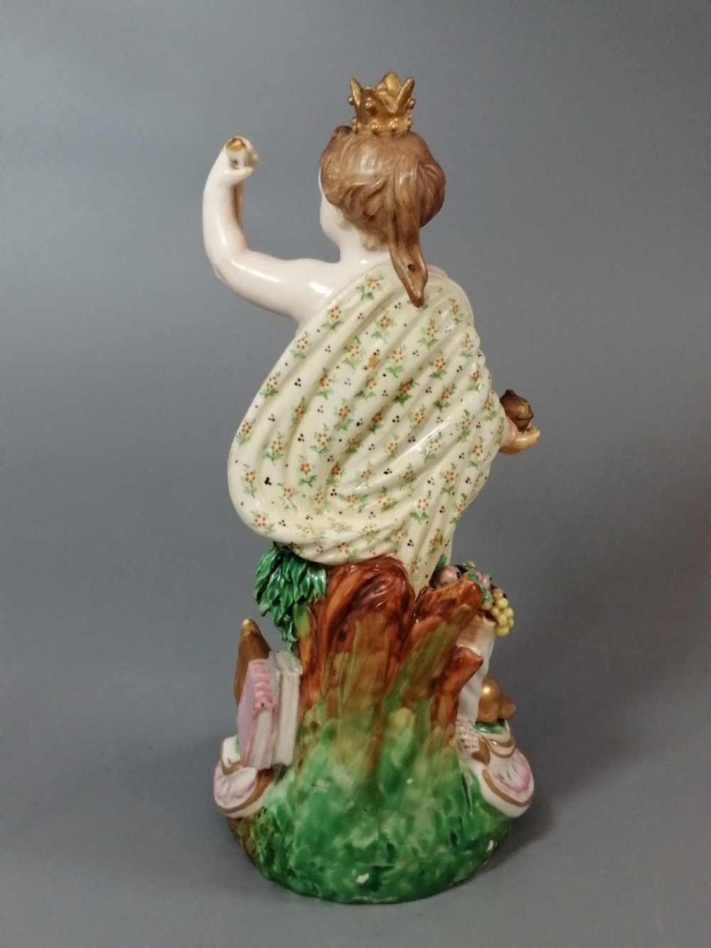 An 18th-century Derby soft-paste porcelain statuette representing Europe, featuring a crowned figure in patterned drapery standing on a gilded scrollwork base. View X