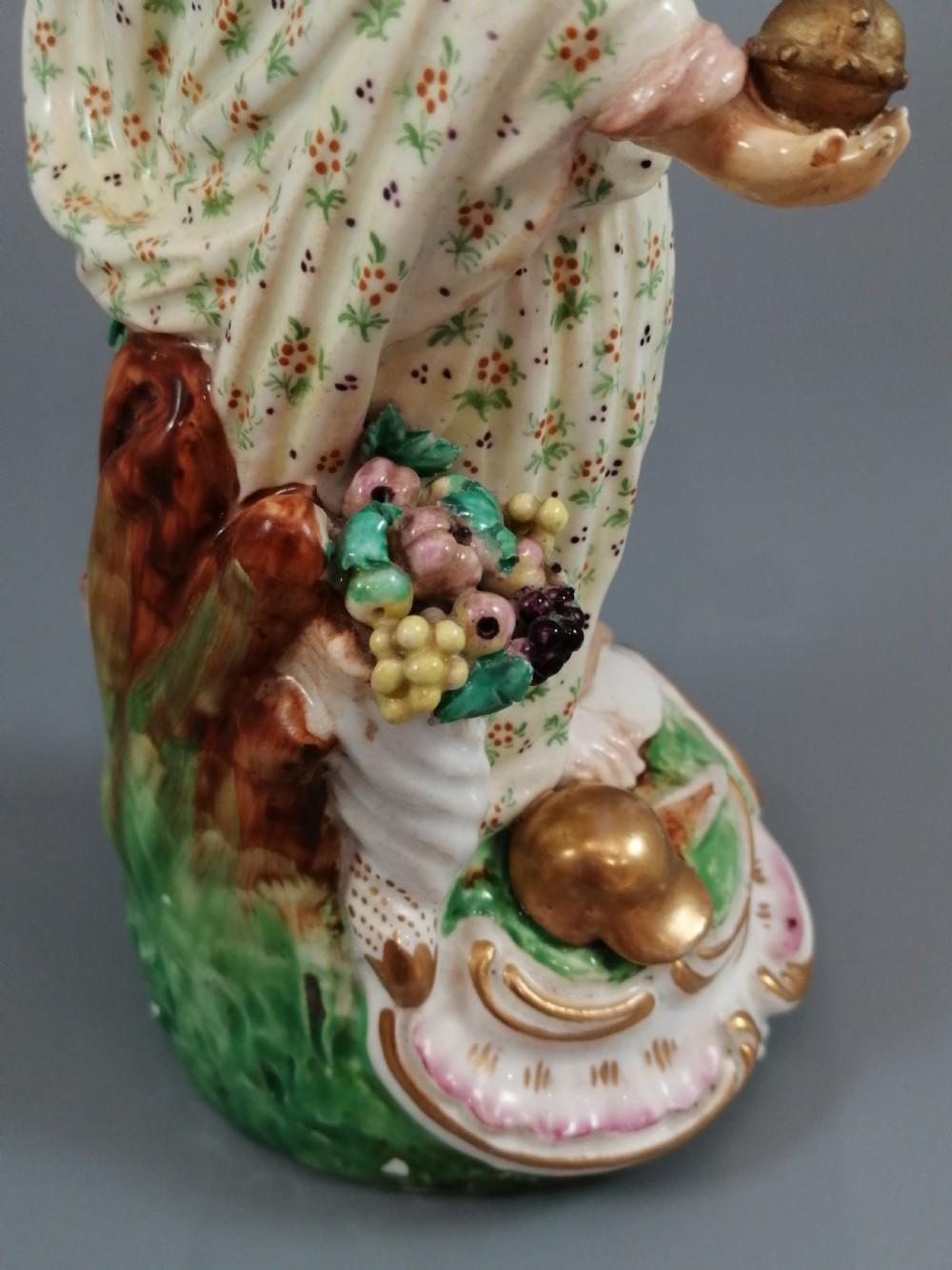 An 18th-century Derby soft-paste porcelain statuette representing Europe, featuring a crowned figure in patterned drapery standing on a gilded scrollwork base. View XIV