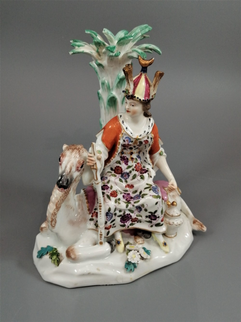 An 18th-century Chelsea soft-paste porcelain figurine depicting an allegorical female figure of Asia seated beside a camel beneath a palm tree.