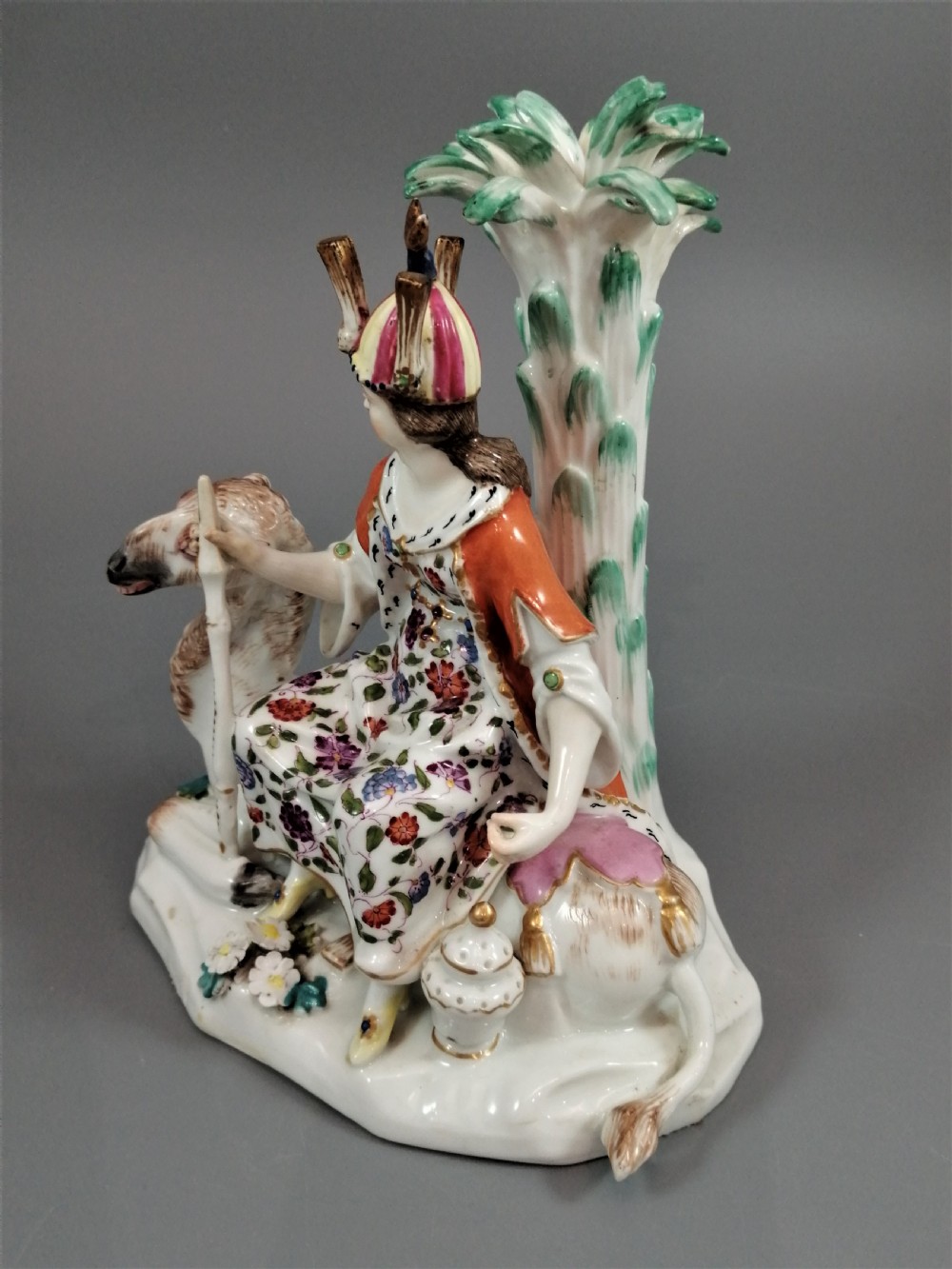 An 18th-century Chelsea soft-paste porcelain figurine depicting an allegorical female figure of Asia seated beside a camel beneath a palm tree. View III
