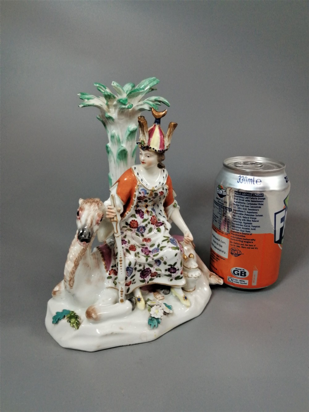 An 18th-century Chelsea soft-paste porcelain figurine depicting an allegorical female figure of Asia seated beside a camel beneath a palm tree. View IX