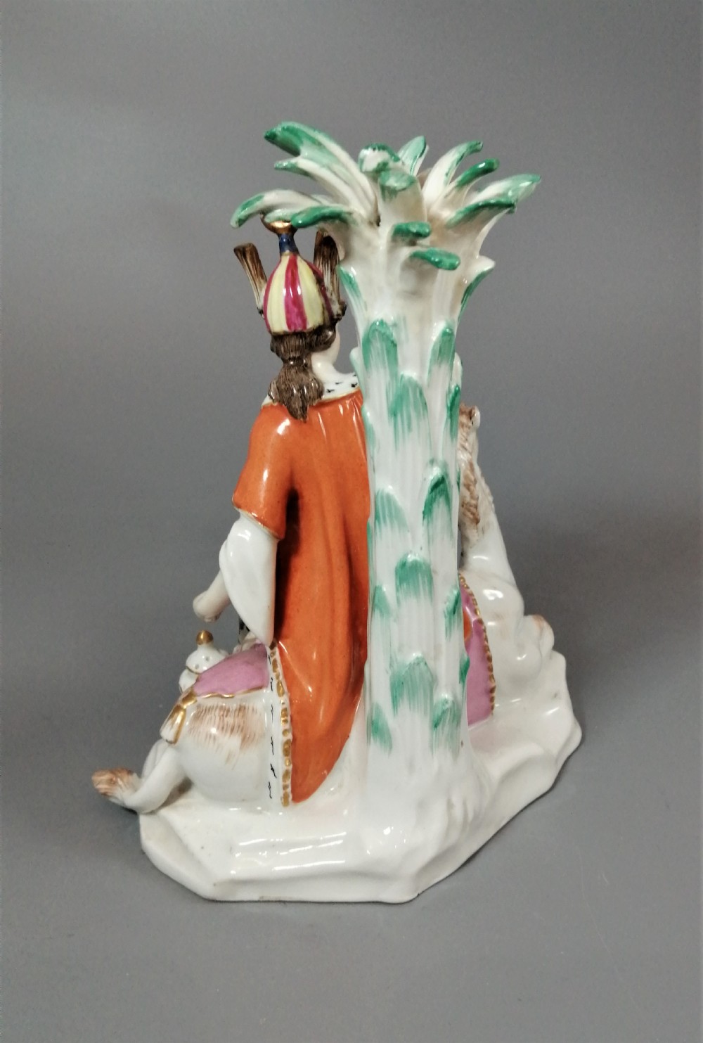 An 18th-century Chelsea soft-paste porcelain figurine depicting an allegorical female figure of Asia seated beside a camel beneath a palm tree. View XIII