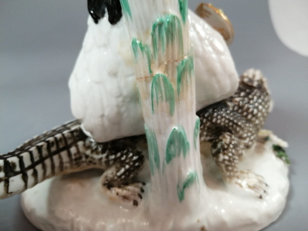 An 18th-century Chelsea polychrome porcelain statuette depicting an allegorical female figure seated on an alligator beside a palm tree. View IX
