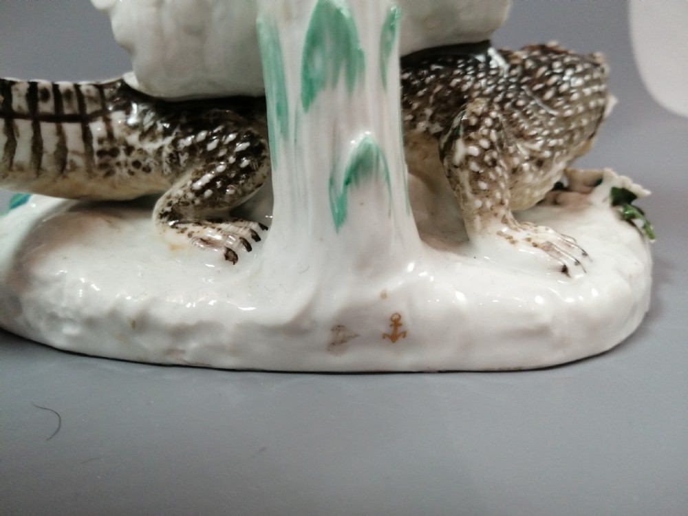 An 18th-century Chelsea polychrome porcelain statuette depicting an allegorical female figure seated on an alligator beside a palm tree. View XIII