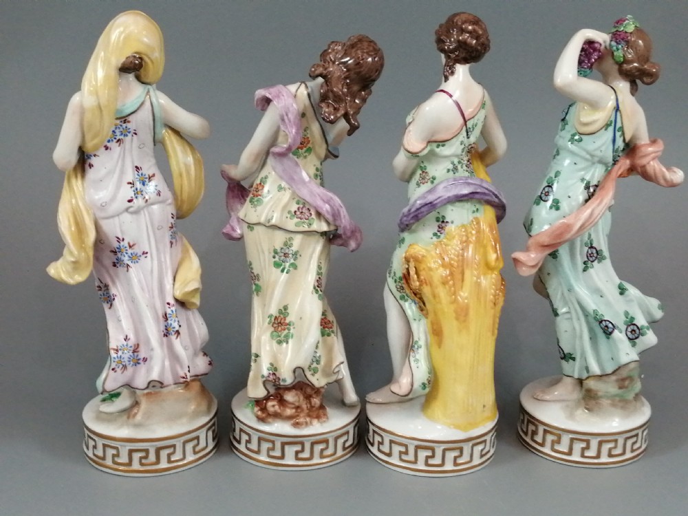 A set of four Sitzendorf polychrome glazed porcelain figurines representing allegories of the Four Seasons, standing on cylindrical Greek key patterned bases. View III