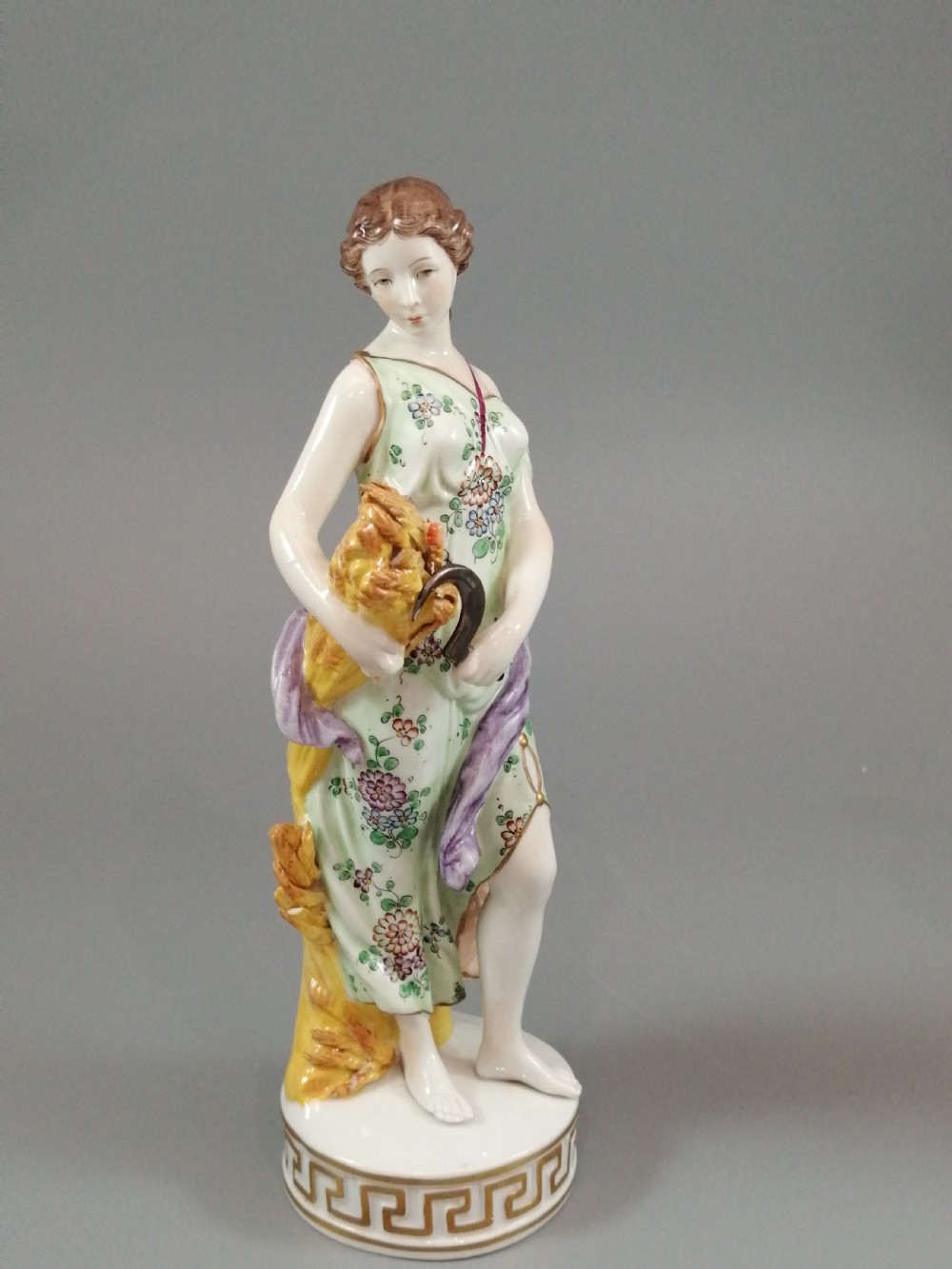 A set of four Sitzendorf polychrome glazed porcelain figurines representing allegories of the Four Seasons, standing on cylindrical Greek key patterned bases. View VII