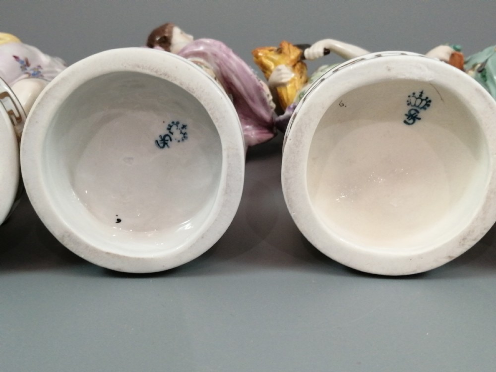 A set of four Sitzendorf polychrome glazed porcelain figurines representing allegories of the Four Seasons, standing on cylindrical Greek key patterned bases. View IX